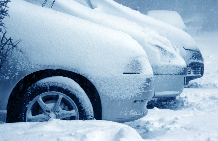 parked cars covered with snow during snowing in winter time